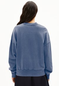 Sudadera de estilo pullover en suave tejido azul jaspeado. Presenta un cuello redondo, hombros caídos y puños y dobladillo de canalé.