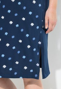 Abito blu con motivo floreale, maniche corte, realizzato in tessuto morbido. Presenta uno spacco laterale e un design di fiori bianchi e azzurri in contrasto.