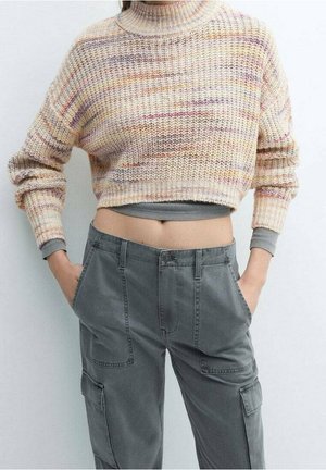Maglione corto in stile uncinetto, di colore crema e pastello, con colletto alto; abbinato a pantaloni cargo grigi con tasche e una vestibilità rilassata.