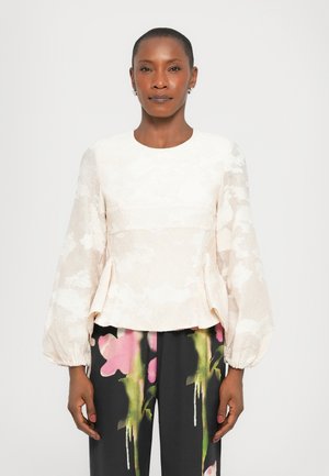 Cream-colored peplum top with textured floral pattern and long sleeves, paired with black pants featuring a vibrant floral print in pink and green.