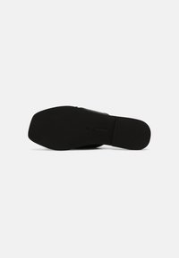 Semelle de chaussure formelle noire à bout carré, surface lisse et talon léger, présentée sur un fond blanc.