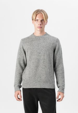 Light gray, textured knit sweater with a round neckline and ribbed cuffs and hem. Paired with dark corduroy pants.