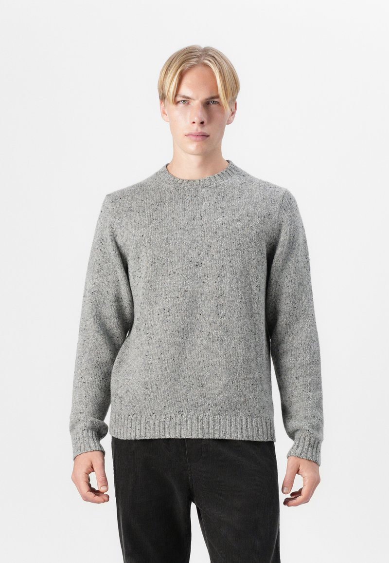 Light gray, textured knit sweater with a round neckline and ribbed cuffs and hem. Paired with dark corduroy pants.