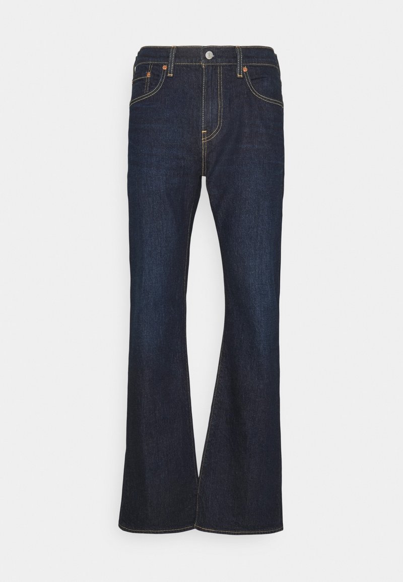 Jean évasé bleu foncé en denim. Il présente un design classique à cinq poches, des coutures dorées et un bouton en métal au niveau de la taille.