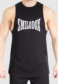 Débardeur noir en coton, avec le mot "SMILODOX" en lettres blanches épaisses sur la poitrine. Conception sans manches avec un col rond.