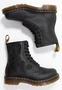 Bottes de combat en cuir noir avec détails brodés de roses, couture orange et semelle en caoutchouc épaisse. Onglet à l'arrière pour un enfilage facile.