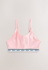 Top roz moale cu bretele subțiri reglabile și bandă elastică albă în partea de jos, repetând cuvântul „NEXT” cu litere negre.