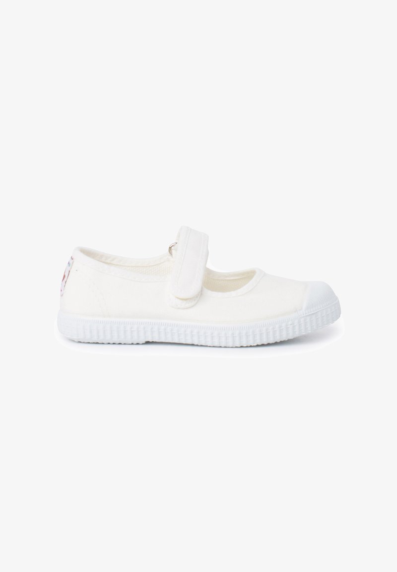 Zapatos Mary Jane de lona blanca con cierre de Velcro, diseño de punta redonda, suela de goma texturizada y un pequeño detalle decorativo en el talón.
