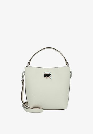White leather bucket bag with a textured finish, silver hardware, and a prominent cartoon pin detail. Includes a detachable shoulder strap.