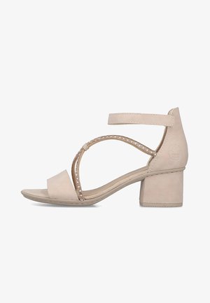 Beige sandal med åben tå og blokhæl, ankelrem samt dekorative krydsede perlebesatte stropper på siden.