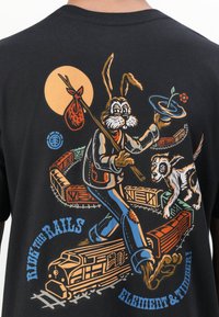 Black cotton t-shirt featuring a colorful graphic of a cartoon rabbit with a stick and a dog, surrounded by trains and text reading "RIDE THE RAILS."