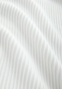 Weißer, gerippter Stoff mit weicher Textur, geprägt von schmalen, gleichmäßig spaceden horizontalen Linien, die ein glattes, wellenartiges Muster erzeugen.