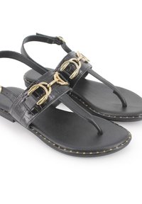 Sandalias negras con parte superior de cuero texturizado, detalle de hardware dorado, tiras delgadas y suela plana con costura decorativa a lo largo del borde.
