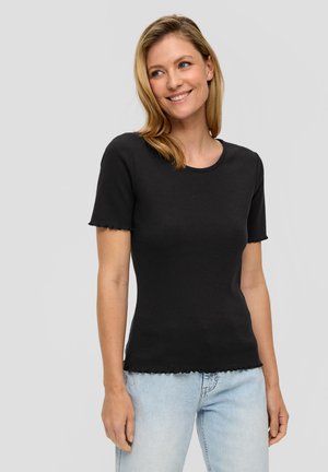 Black short-sleeve fitted top with a ribbed texture and scalloped hem, worn with light blue denim jeans. Simple round neckline.