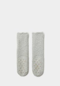 Para jasnoszarych puszystych skarpetek z antypoślizgowymi silikonowymi kropkami na podeszwach, leżących płasko na białym tle.