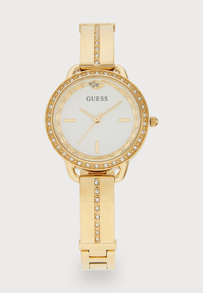 Gold wristwatch with a round face, white dial, gold hour markers, and a crystal-encrusted bezel. Features a metal band with accent stones.
