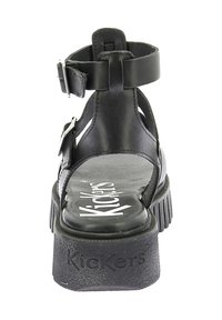 Zwarte leren platform sandalen met verstelbare enkelriem, gestructureerde zool en prominent "Kickers" logo op de binnenzool.