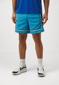  pantalones cortos atléticos de malla azul claro con rayas negras y blancas, combinados con zapatillas blancas y negras y calcetines blancos hasta la mitad de la pantorrilla.