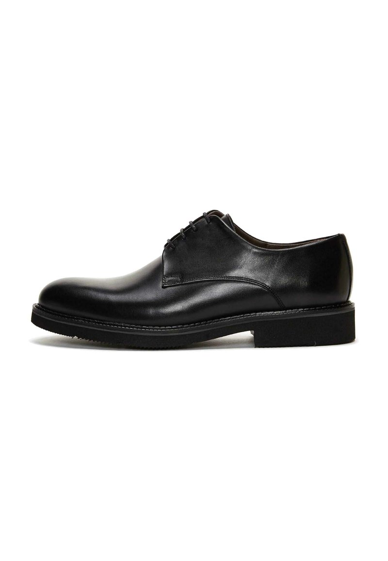 Zapato de vestir de cuero negro con superficie lisa, punta redonda y diseño con cordones. Suela de goma resistente, costuras en contraste a lo largo de los bordes.