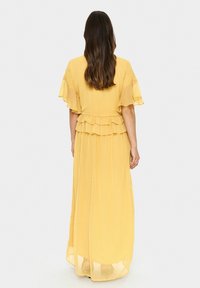 Yellow maxi dress with short, ruffled sleeves, a tiered waistline, and a flowing, pleated skirt. Lightweight, sheer fabric with a smooth texture.