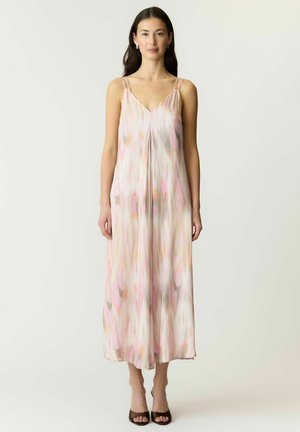 Woman with long dark hair wearing a sleeveless, loose-fitting midi dress with soft pastel pink, peach, and beige abstract patterns, standing straight.