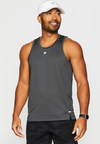 Dunkelgraues Sporttanktop mit strukturierter Oberfläche, präsentiert mit einem weißen Logo, ärmellosem Design und seitlichen Schlitzen für Bewegungsfreiheit. Weißer Hut getragen.