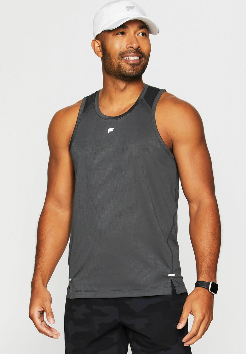 Dunkelgraues Sporttanktop mit strukturierter Oberfläche, präsentiert mit einem weißen Logo, ärmellosem Design und seitlichen Schlitzen für Bewegungsfreiheit. Weißer Hut getragen.