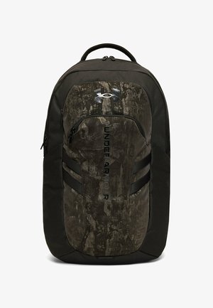 Mochila Under Armour negra y marrón oscuro con textura, con bolsillo delantero con cremallera y asa superior sobre fondo blanco.