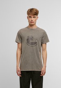T-shirt en coton gris à manches courtes, col rond et finition texturée. Présente un design imprimé d'un palmier et du texte à l'avant.