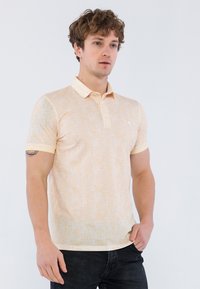 Polo de manga corta en color amarillo claro con un patrón texturizado y cuello en contraste. La tela parece suave y transpirable.
