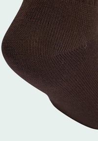 Brązowa skarpetka z dzianiny o prążkowanej teksturze, z gładkim obszarem palców i dopasowanym krojem. Obraz koncentruje się na górnej części skarpetki.