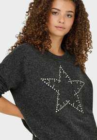 Pull en charbon fabriqué en laine douce avec une coupe décontractée, présentant un motif d'étoile décoré de strass transparents sur le devant.