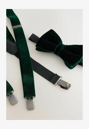 Grüner Samt-Fliegenbinder neben grünen Samt-Trägern und einem schwarzen elastischen Riemen. Metallclips und texturierte Stoffdetails sind sichtbar.