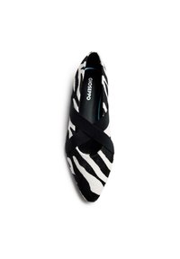 Zapato plano con estampado de cebra en blanco y negro, con punta afilada, que cuenta con una tira elástica cruzada negra en la parte superior y un forro interior suave.