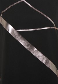 Tissu noir avec des lignes métalliques argentées diagonales et courbes formant un motif géométrique abstrait.