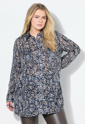 Blusa trasparente blu navy con motivo paisley in marrone, crema e blu. Presenta una chiusura con bottoni sul davanti, due tasche sul petto e maniche lunghe.
