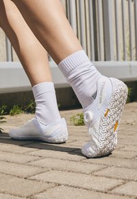 White Merrell shoes with a textured sole, featuring a BOA dial closure and perforated mesh upper, worn with white socks.