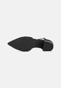 Zapato de tacón alto negro con punta afilada, suela texturada y una correa. El tacón es elegante con un acabado mate.