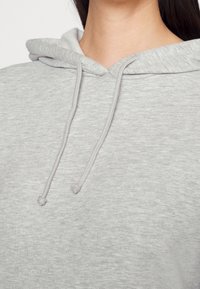 Grijze hoodie met een trekkoord, zachte textuur en een ontspannen pasvorm. Heeft een comfortabele kap en geen zichtbare patronen of accenten.