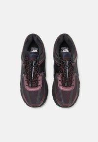 Scarpe da corsa Nike in viola scuro e nero, con una tomaia testurizzata, lacci riflettenti e una suola ammortizzata per comfort e supporto.