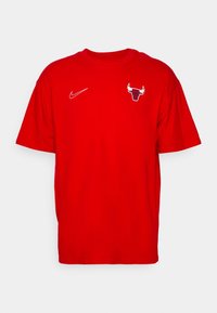 Camiseta roja de manga corta hecha de algodón, con un logo blanco de Nike en el lado izquierdo del pecho y un logo de los Chicago Bulls en el centro.