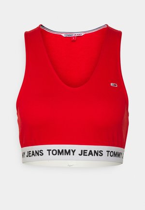 Raudonas medvilnės trumpas viršus su giliu V iškirpte. Yra balta juosta su užrašu "TOMMY JEANS" juodu spalva. Lygus paviršius, sportiškas dizainas.