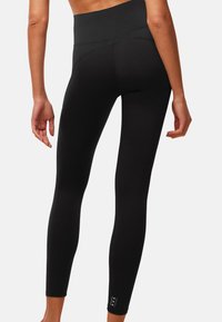 Czarne legginsy z wysokim stanem. Gładka tekstura i elegancki krój, z małym logo na kostce.