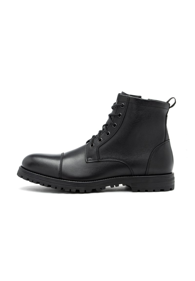 Botas de tobillo de cuero negro con punta redondeada, cierre de cordones en el frente, suela de goma y paneles laterales texturizados. Incluyen un tirador para facilitar el calzado.