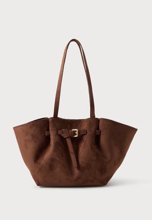 Sac cabas en daim marron avec de longues anses d’épaule, une forme évasée et une sangle décorative à boucle sur le devant.