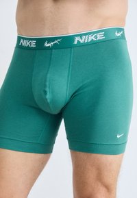 Zeleni bombažni boxerji z mešanico blaga in tesnim prileganjem, z belim Nike logotipom na elastičnem pasu in kontrastnimi šivi.