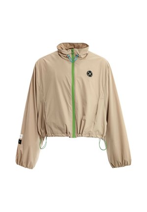 Chaqueta corta cortaviento de color marrón claro con puños elásticos, cremallera verde, cordones en el cuello y el dobladillo, y un pequeño logo redondo en el pecho.