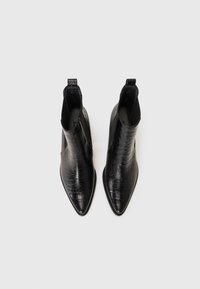 Bottines noires à talon bas avec un bout pointu, fabriquées en simili cuir texturé imitation crocodile. Dotées d'un design épuré et de languettes de tirage.