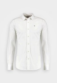 Hvit langermet skjorte med knapper og spiss krage, laget av glatt stoff. Har en liten logo på venstre bryst og standard mansjettknapper.