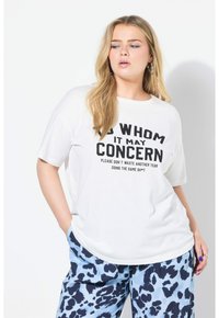 Witte T-shirt met korte mouwen en zwarte grafische tekst. Gecombineerd met een blauwe broek met een donkerblauw en zwart gevlekt patroon.